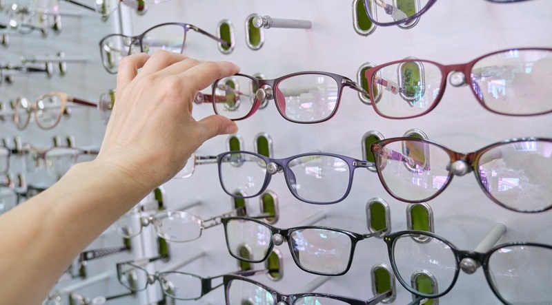 showcase with glasses in the store, hand choosing glasses