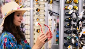 profile of a woman wearing a hat and trying on sunglasses in a store Eyewear Trends